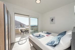 A bedroom with a bed, a window, and a view of the outside.