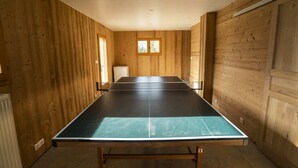 Une pièce avec une table de ping-pong, des murs en bois et une fenêtre.