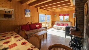 Une chaleureuse cabane en bois comprenant un coin repas, un canapé et une cheminée.