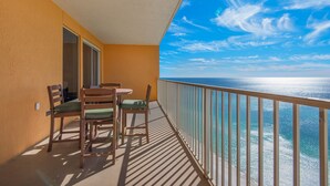 Uma varanda com vista para o oceano, cadeiras de madeira e uma mesa.