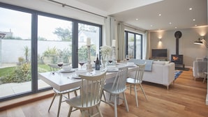 Una sala de estar moderna con comedor, ventanas amplias, chimenea y televisor.