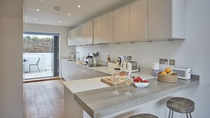Una cocina moderna con una isla grande, electrodomésticos integrados y vistas al exterior.