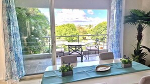 Ein Balkon mit Tisch, zwei Stühlen und Blumentöpfen, gedeckt für zwei Personen.