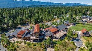 A lodge with multiple buildings, a parking area, and a forested backdrop. - Family-Friendly Luxury | Great Amenities + 1PM Check-In & Check-Out (Cle Elum)