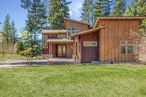 A modern two-story house with a wooden exterior, a covered porch, and a well-maintained lawn.