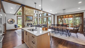 A spacious kitchen with a large island, wooden cabinets, and a stone accent wall. - Family-Friendly Luxury | Great Amenities + 1PM Check-In & Check-Out (Cle Elum)