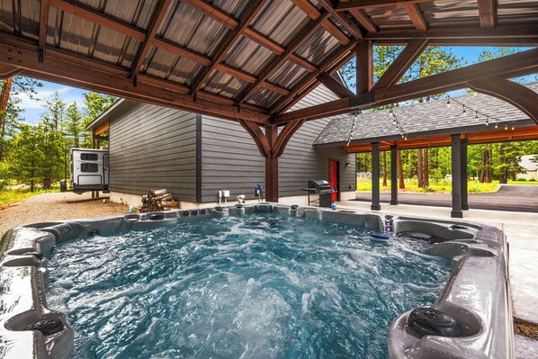 A hot tub area with a covered roof, a wooden deck, and a house in the background.