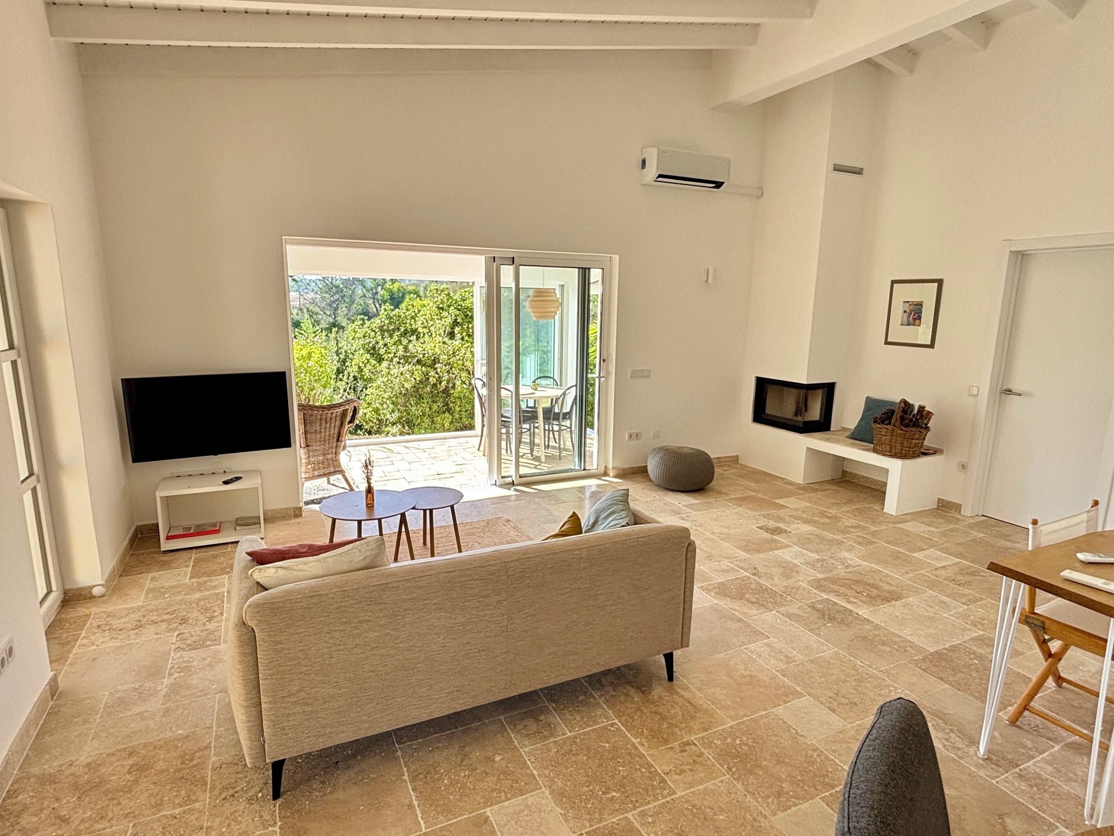 A modern living room with a sofa, TV, and a dining area with a table and chairs.