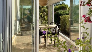 Ein modernes Haus mit einer Schiebetür, die auf eine Terrasse mit Tisch und Stühlen führt.