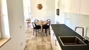 Eine moderne Küche mit schwarzem Arbeitsplatz, einer Spüle und einem Essbereich mit Tisch und Stühlen.