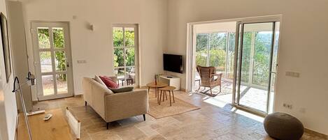 A spacious living room with a sofa, a TV, and a dining area.