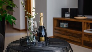 Ein Tisch mit einer Champagnerflasche, einem Glas und einer Vase mit grünen Blättern.