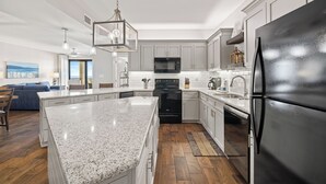 A modern kitchen with granite countertops, stainless steel appliances, and a large island. - Romar House 603A by Liquid Life (Orange Beach)