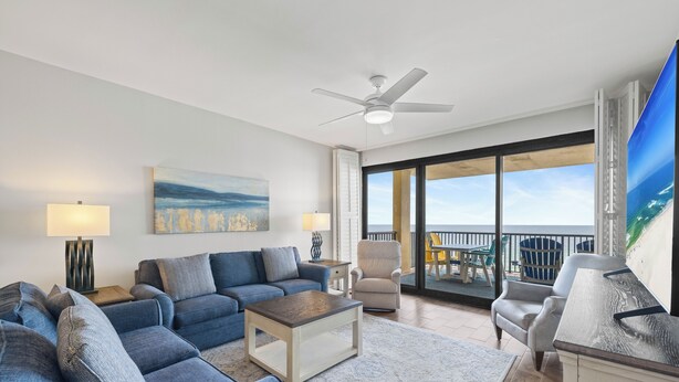 A living room with a sofa set, a coffee table, a chair, a TV, and a balcony with a view. - Romar House 603A by Liquid Life (Orange Beach)