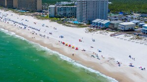 A beach with numerous umbrellas and people. - Romar House 603A by Liquid Life (Orange Beach)