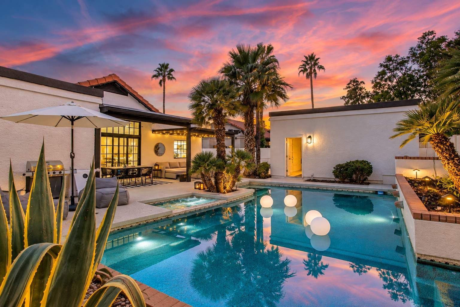 A pool area with a sunset view, a barbecue setup, and a patio with seating.