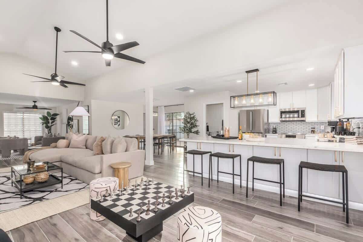 A modern kitchen with a central island, bar stools, and a dining area with a round table and chairs.