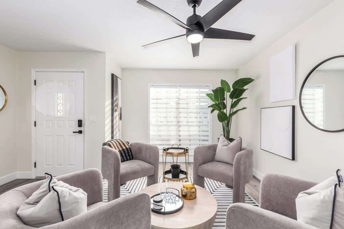 Un salon moderne avec deux canapés gris, une table basse et un ventilateur de plafond.