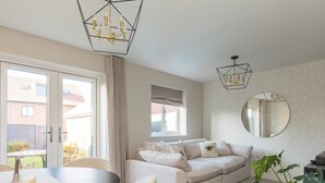 A modern living room with a sofa, a dining table, and a large window.