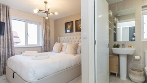 A modern bedroom with a large bed, a chandelier, a bathroom with a sink and mirror, and a view of the outside.