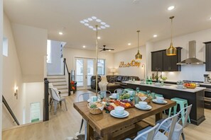 A modern kitchen with dark cabinets, a central island, and pendant lighting. - ​🎉Celebrate in Style! Game Room, 🎱Pool Table,  💃🏼 Dance Pole! (Nashville)