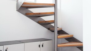 A spiral staircase with wooden steps and metal railings, leading to a landing with cabinets. - Luxury maisonette in Ilioupoli (Ilioupoli)