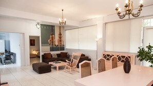 A modern living room with a sofa, chairs, a dining table, and a chandelier. - Luxury maisonette in Ilioupoli (Ilioupoli)