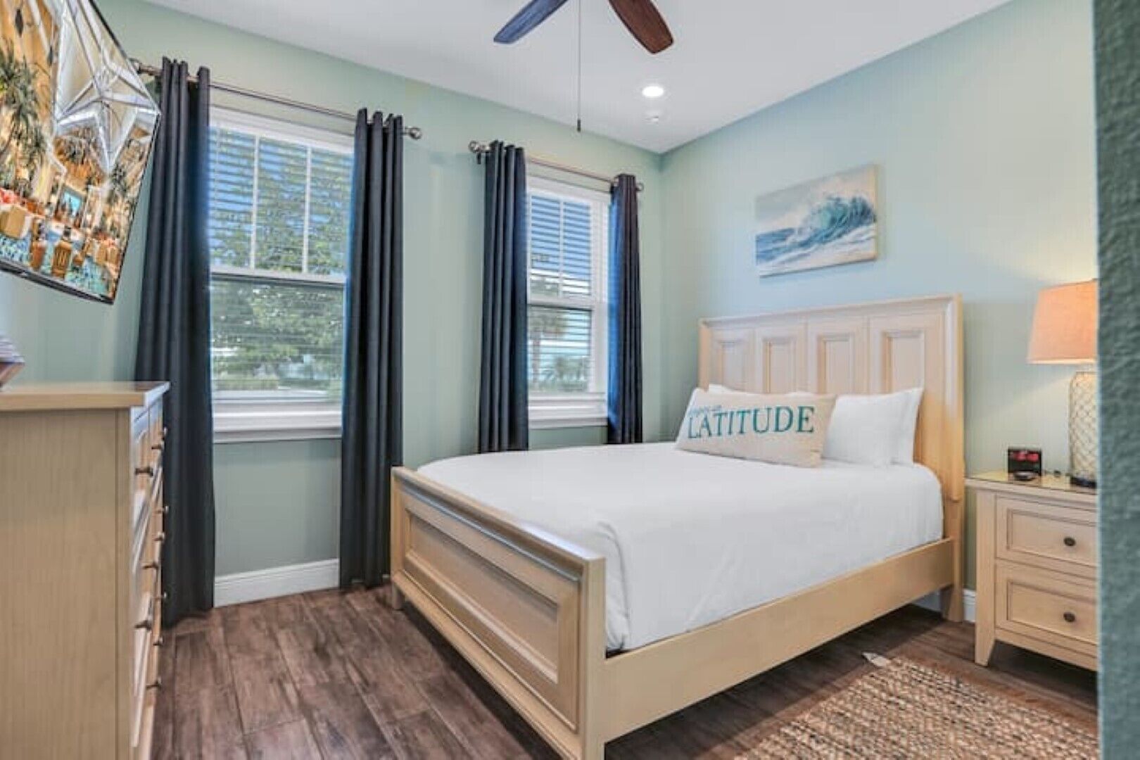 Un dormitorio con cama de madera, mesita de noche, cómoda y ventilador de techo.