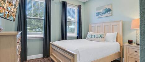 Un dormitorio con cama de madera, mesita de noche, cómoda y ventilador de techo.
