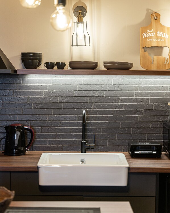 A kitchen with a white sink, black brick backsplash, and a wooden countertop. - GM Luxury Suites Kalavryta (Kalavrita)
