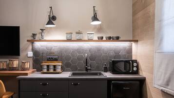 Una cocina moderna con encimera negra, microondas, fregadero y dos lámparas colgantes.