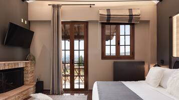A bedroom with a fireplace, a bed, a window with curtains, and a view of the outdoors.