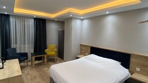 Una habitación de hotel moderna con una cama grande, un escritorio y una silla.