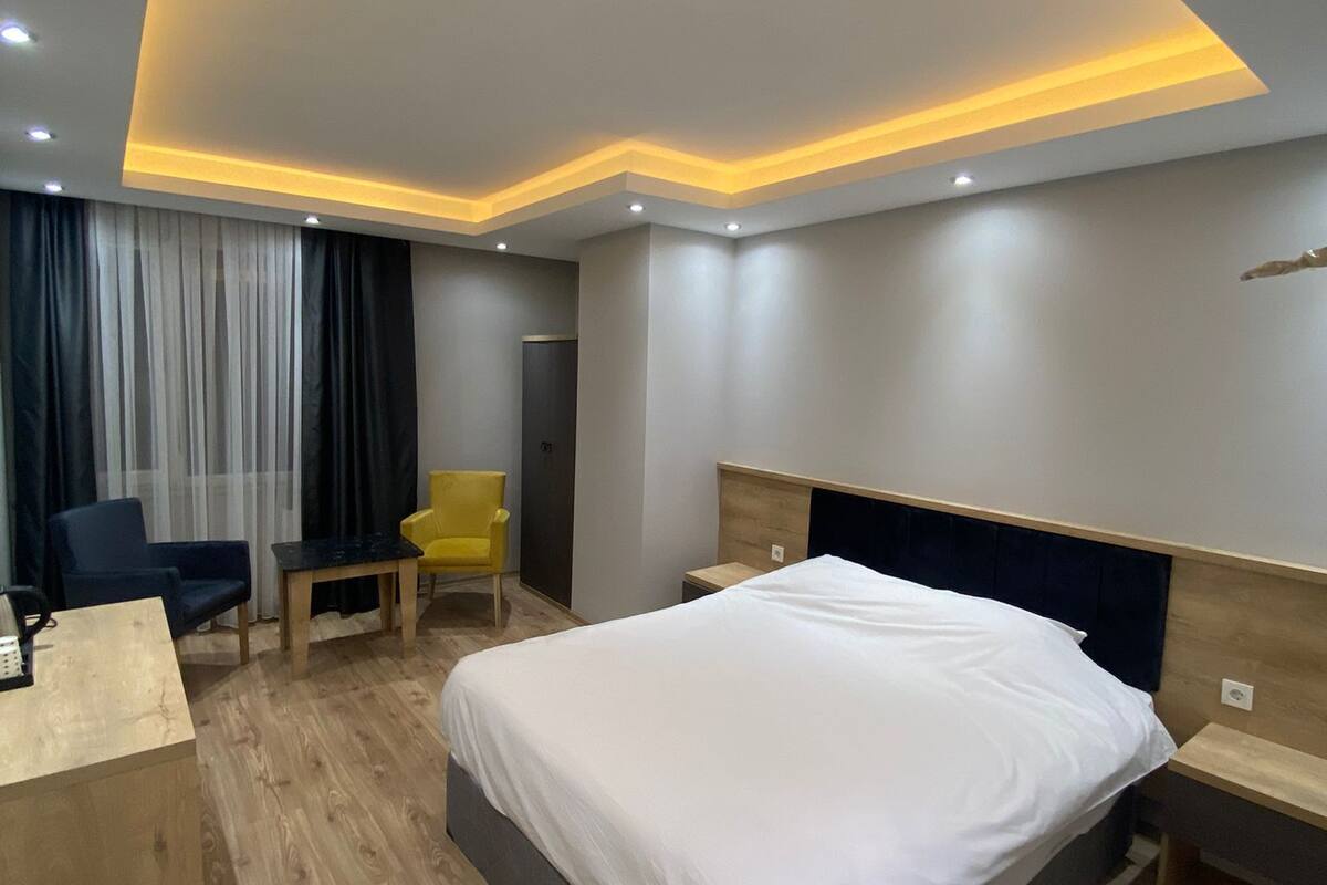 A modern hotel room with a large bed, a desk, and a chair.