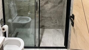 Un baño moderno con ducha de vidrio, inodoro y lavamanos.