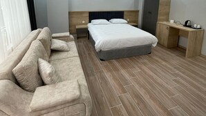 Un dormitorio moderno con cama, sofá, escritorio y armario.