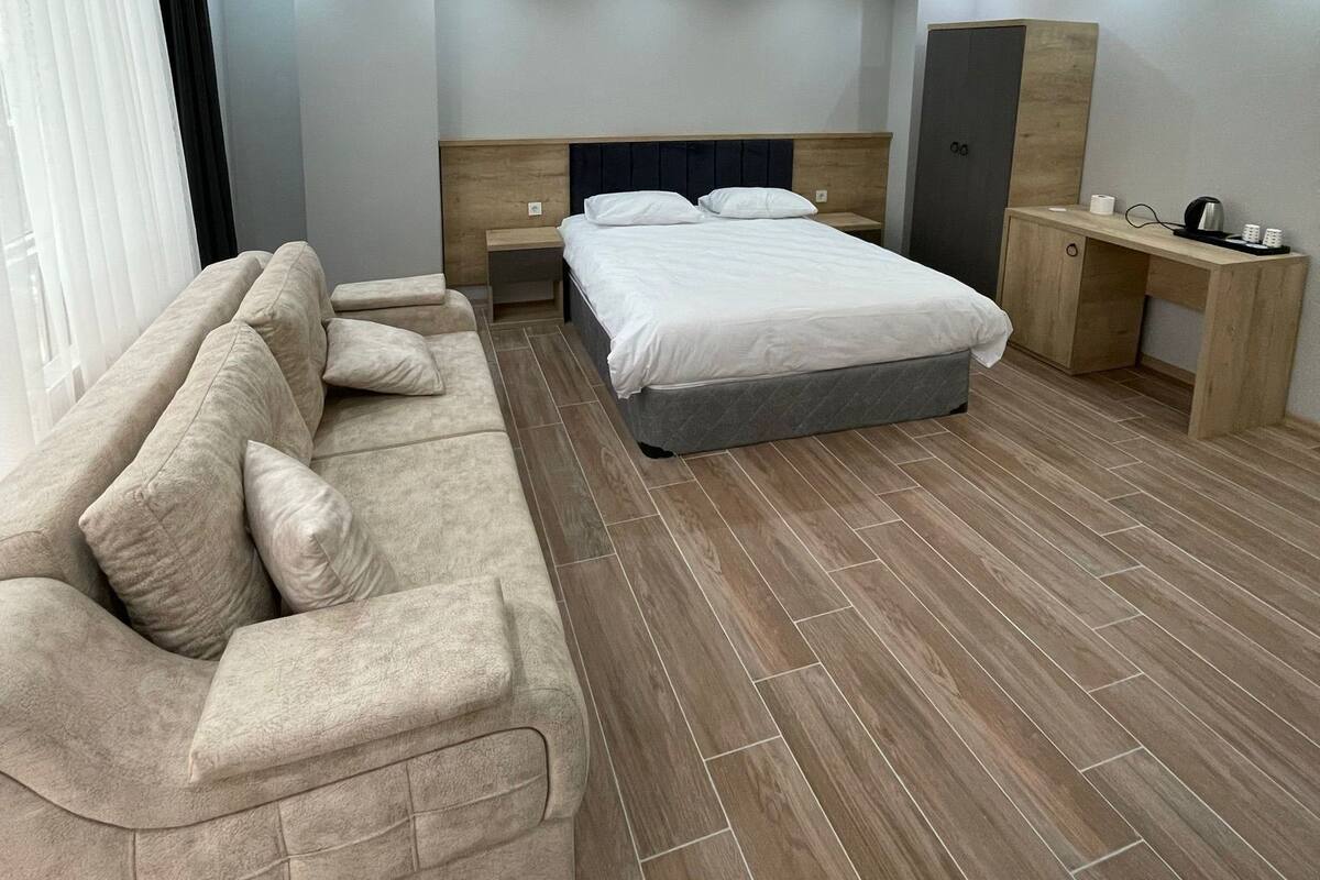 A modern bedroom with a bed, a sofa, a desk, and a wardrobe.
