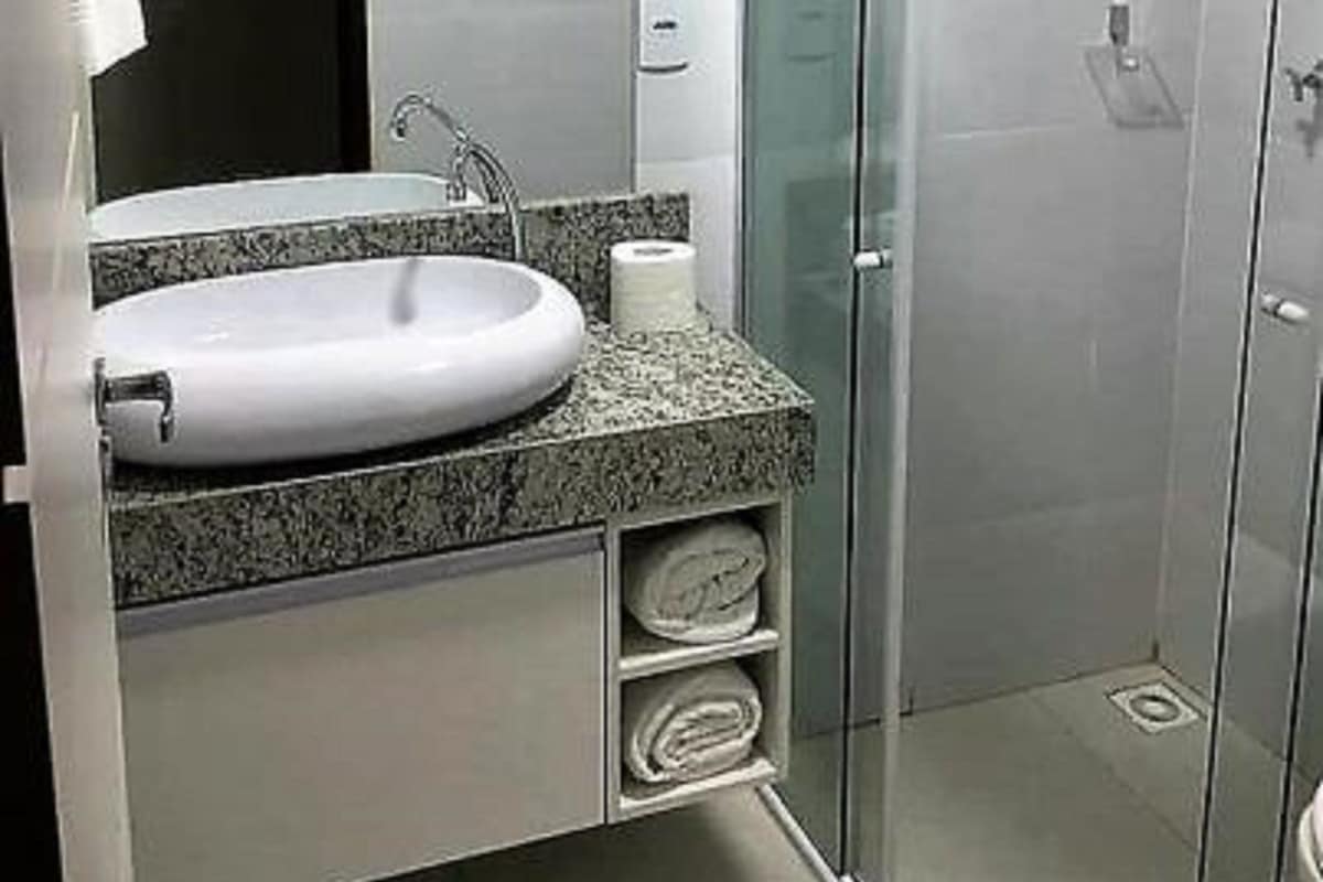 Un baño moderno con lavamanos blanco, encimera de granito y cabina de ducha con mampara de vidrio.