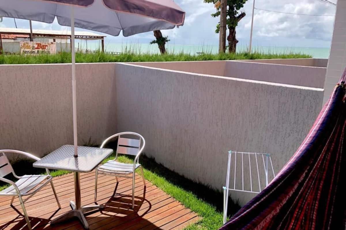 A patio with a table and chairs, a hammock, and a view of the ocean.