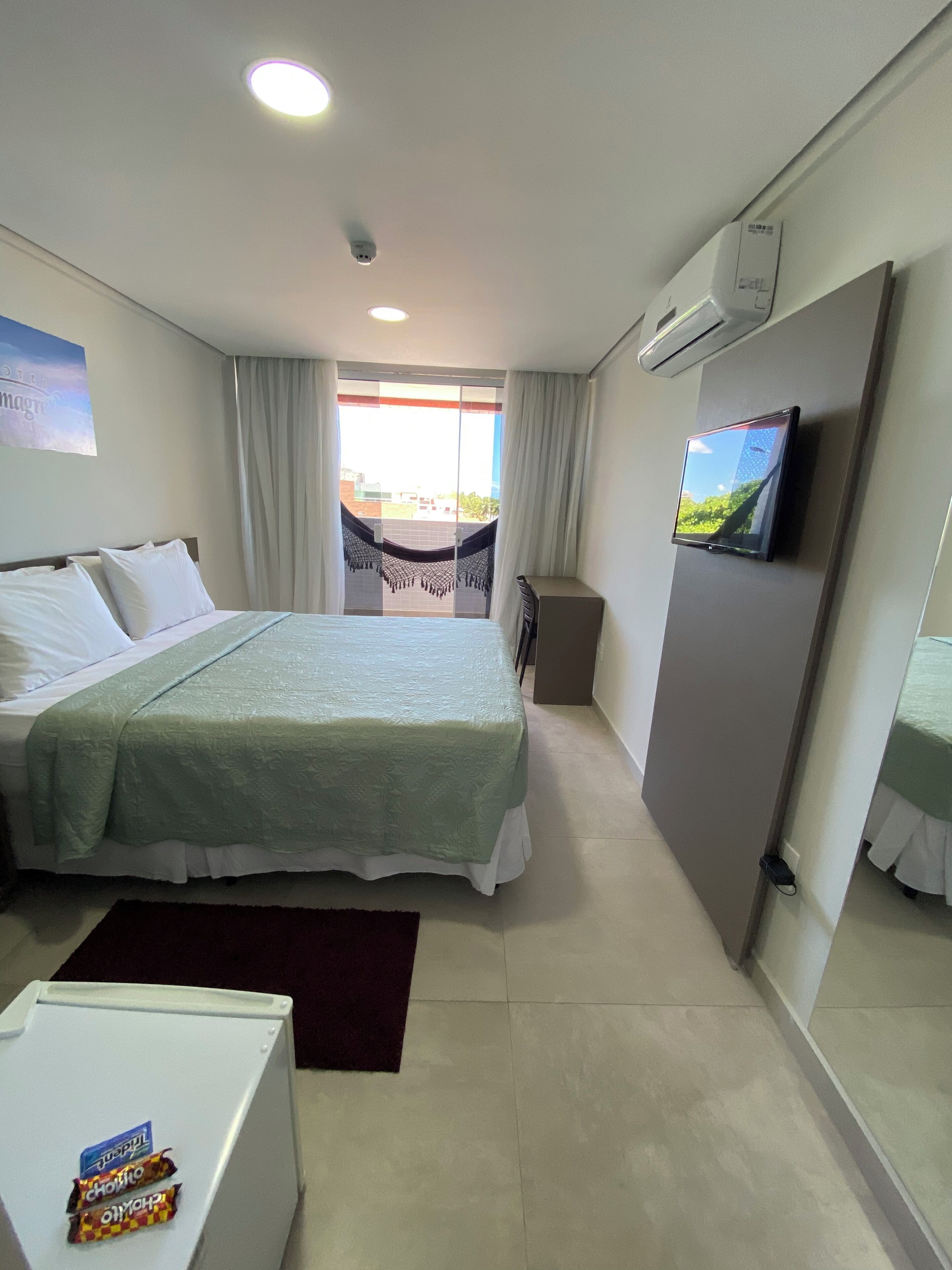 Habitación de hotel con cama, televisión, minibar y vistas al exterior.