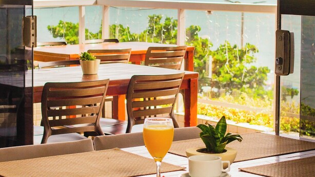 A dining table with a glass of orange juice, a plate of fruit, and a potted plant.