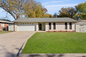 A single-story house with a garage, a front lawn, and a brick exterior.