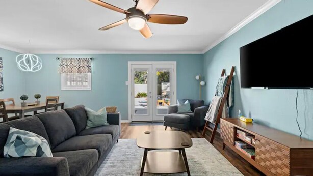 Ein Wohnzimmer mit Deckenventilator, Fernseher, Sofa, Couchtisch und TV-Schrank.