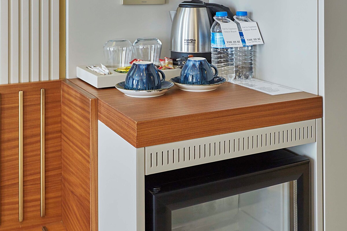 A compact minibar with a refrigerator, a coffee maker, and a water dispenser.