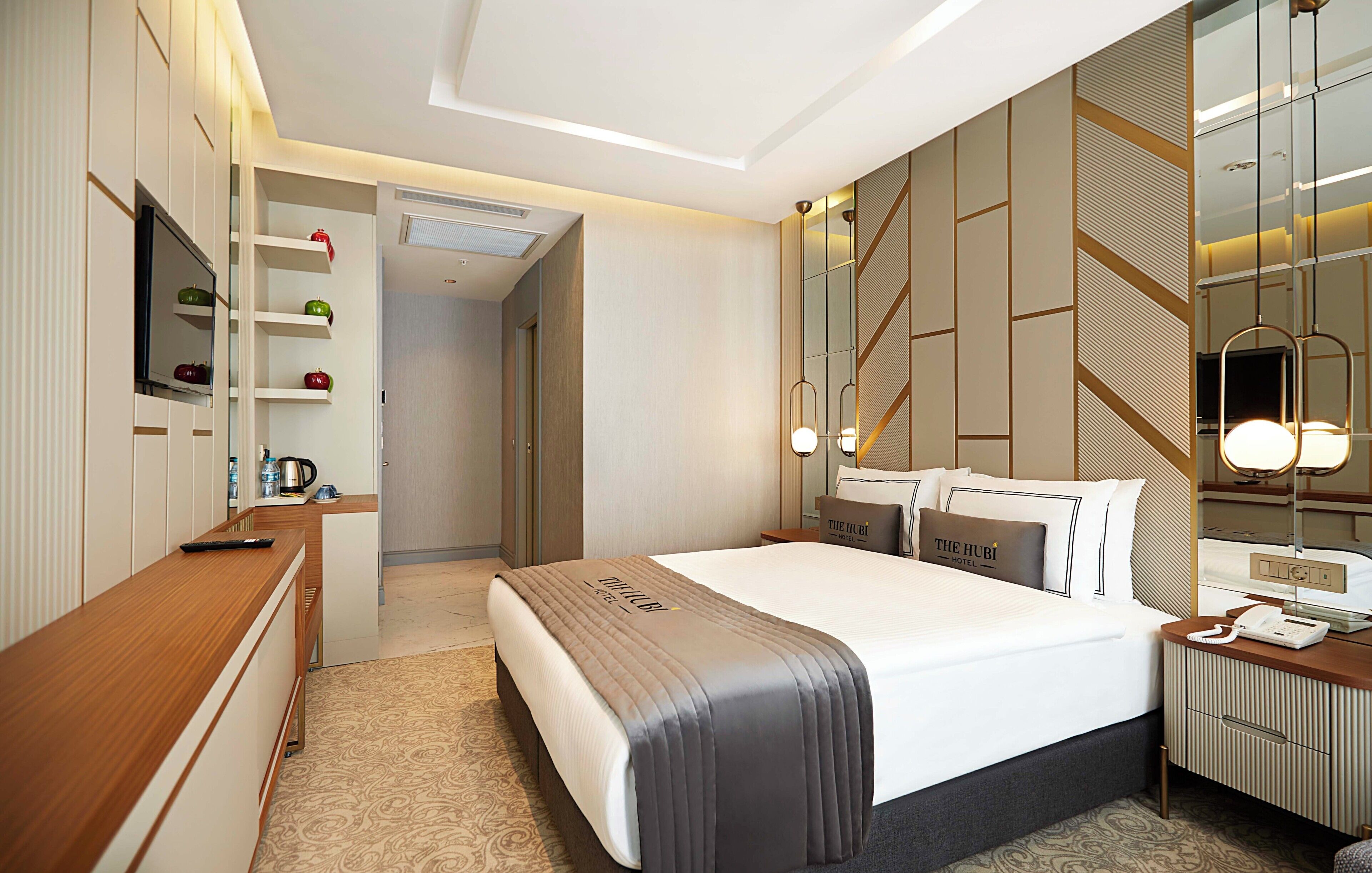 A hotel room with a bed, bedside table, TV, and a mirror.