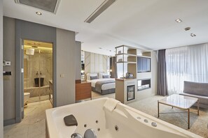 A modern hotel room with a large bathtub, a sofa, a TV, and a shower area. - The Hubi Hotel (Istanbul)
