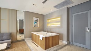 A modern bathroom with a freestanding bathtub, a seating area with a sofa and table, and a door with a handle. - The Hubi Hotel (Istanbul)