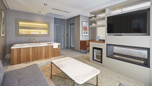 A modern hotel room with a wooden vanity, a large flat-screen TV, a built-in fireplace, and a small seating area. - The Hubi Hotel (Istanbul)