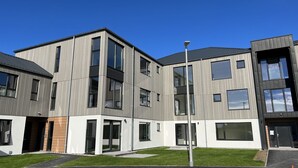 A modern multi-story residential building with a flat roof, large windows, and a well-maintained lawn. - Caledonia Place - Retreat Group (Aviemore)