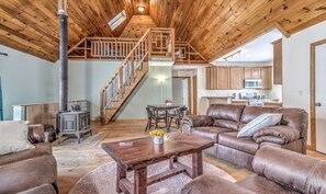 A spacious living room with a high wooden ceiling, a fireplace, a dining area with a table and chairs, and a kitchen in the background. - Secluded Cottage (Peru)